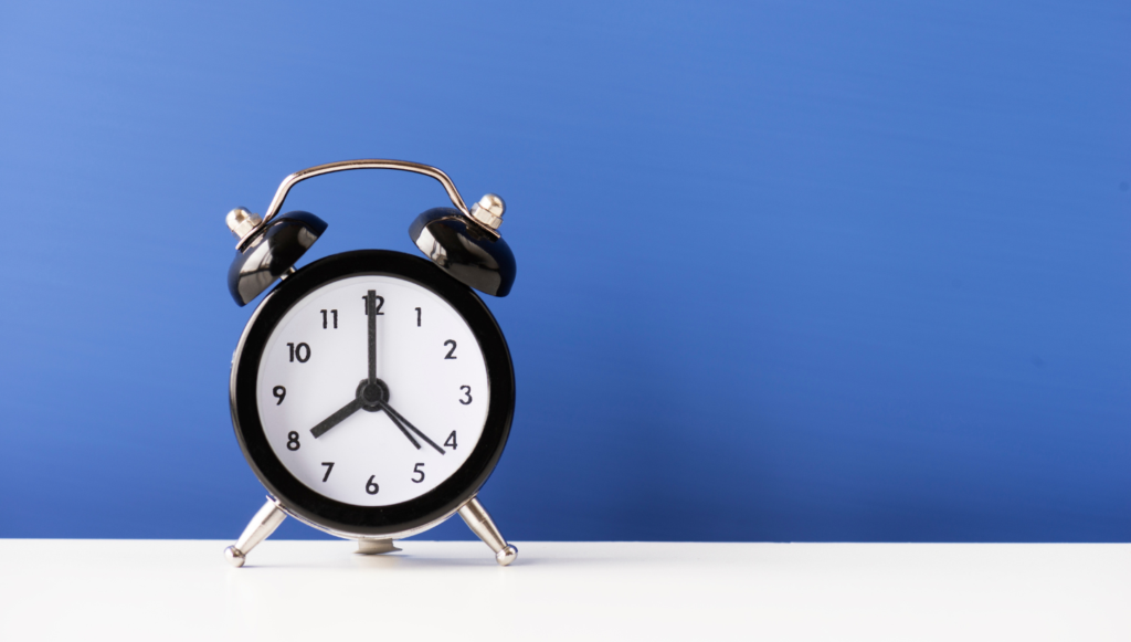 Black alarm clock on a white surface with a blue background